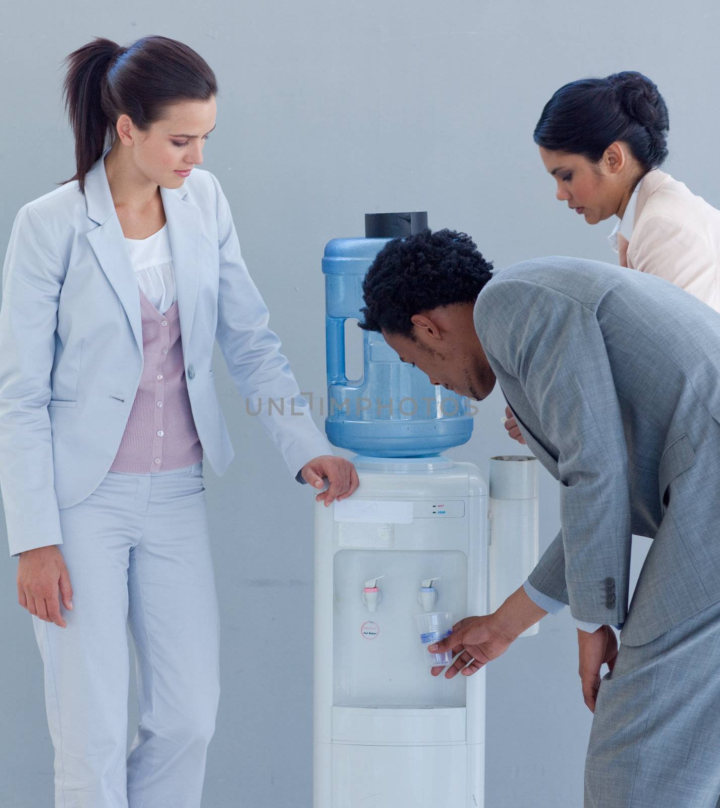 Business people drinking from a water cooler in office