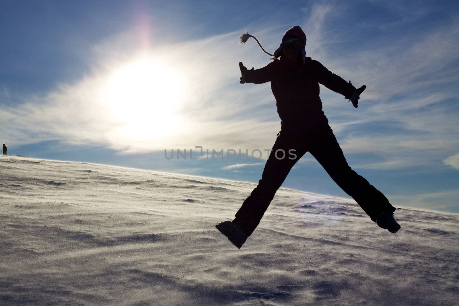 Silhouette of jumping girl on snow against the sun, concept of youth, energy, active life