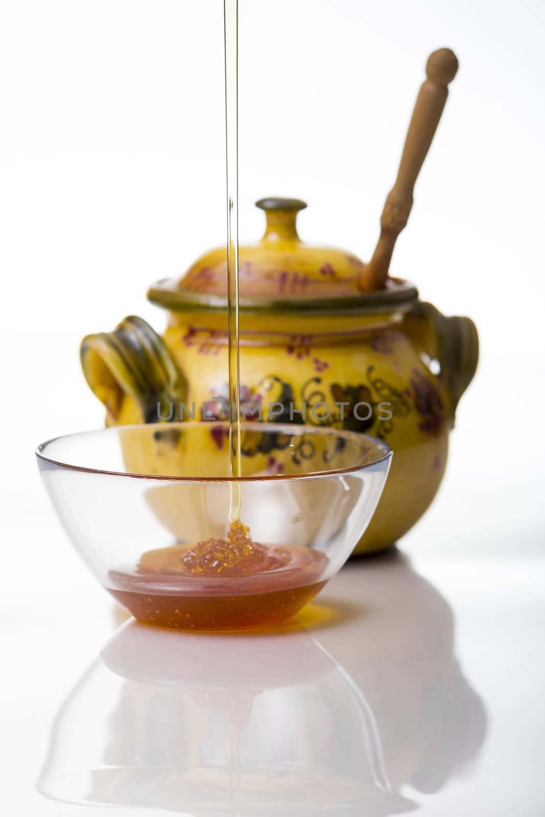 Honey pouring to glass mug on white background