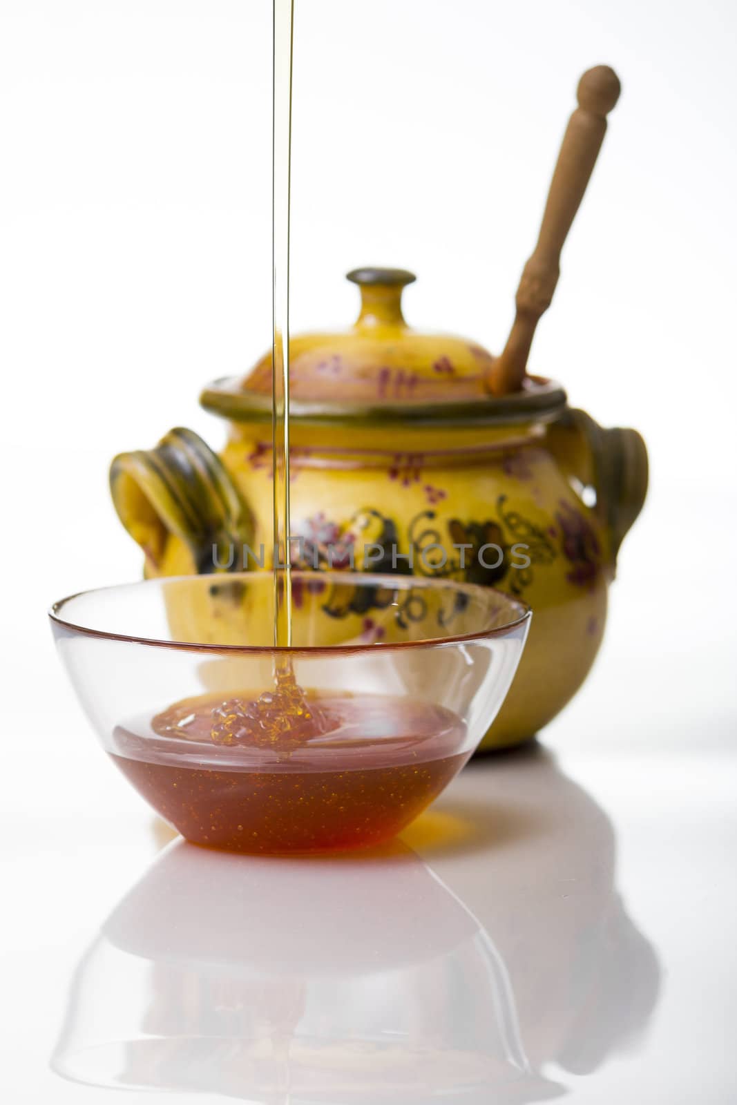 Honey pouring to glass mug on white background