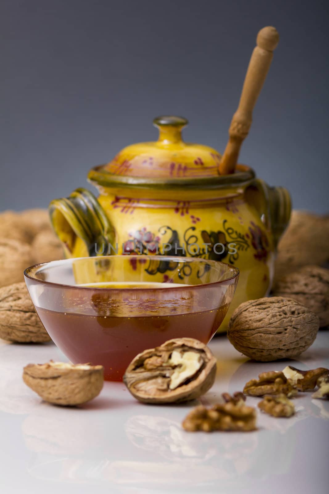 Transparent mug full of honey, honey jar and walnut