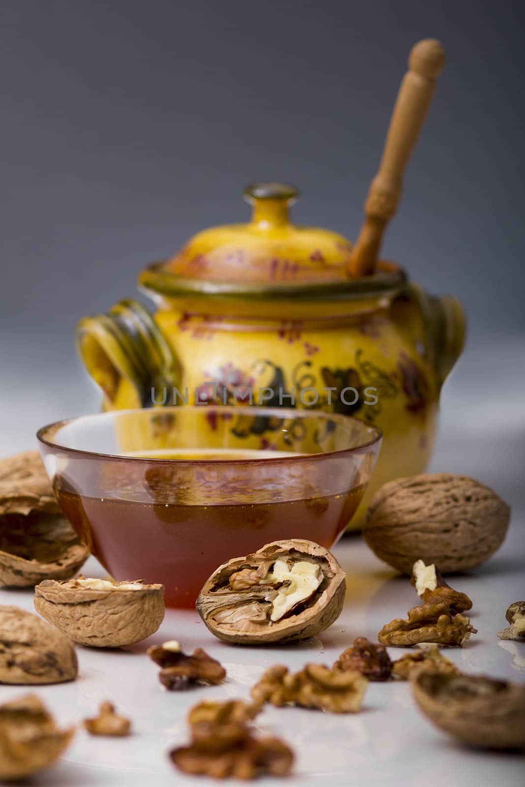 Transparent mug full of honey, honey jar and walnut