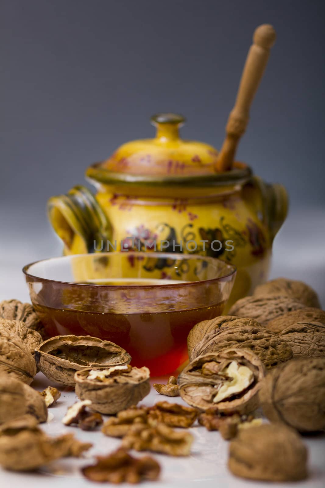 Transparent mug full of honey, honey jar and walnut