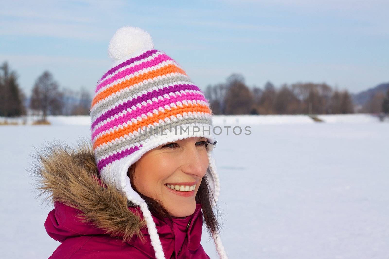 Smiling young woman wearing knitted winter cap with natural winter background