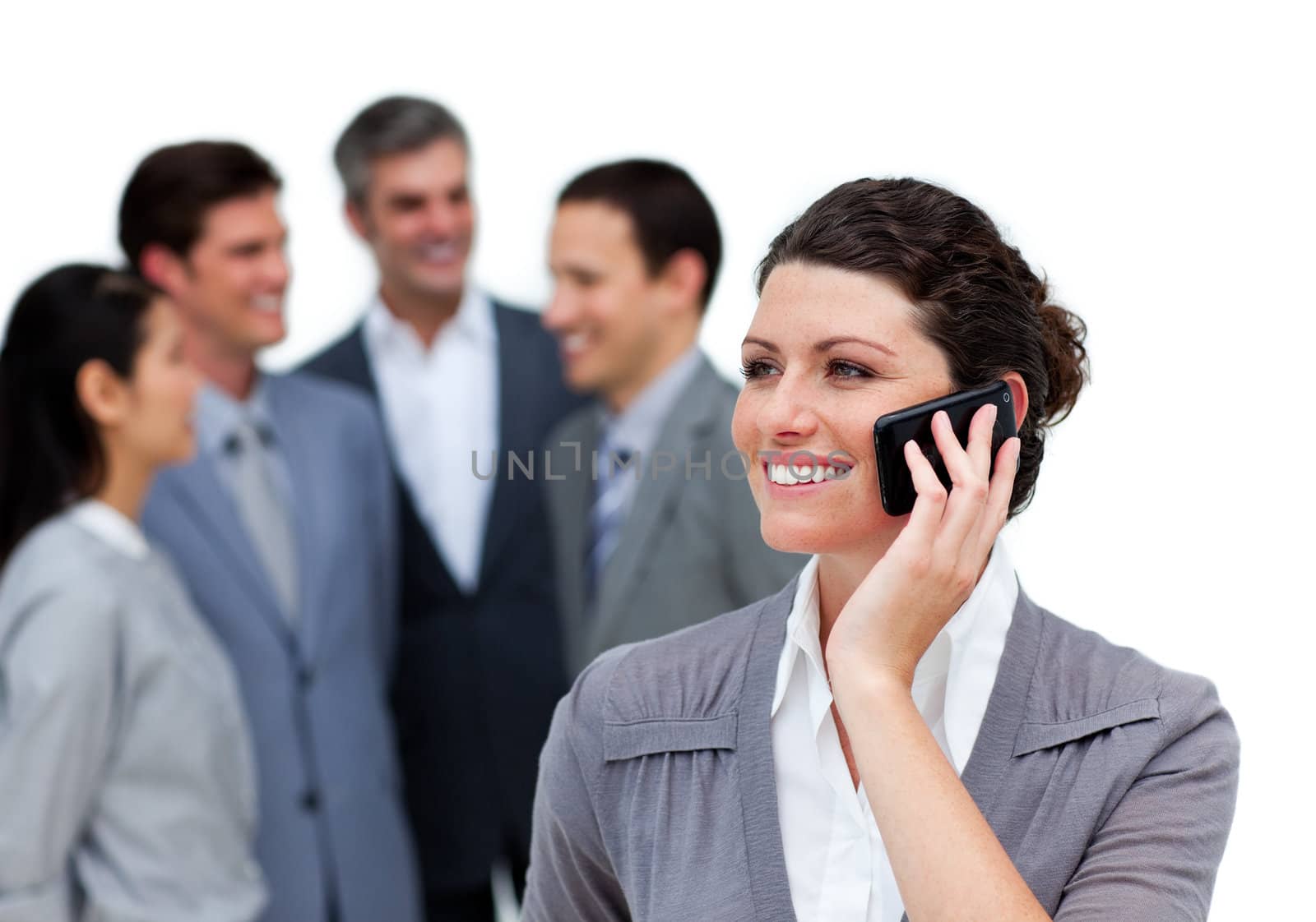 Caucasian woman talking on phone in front of her team against a white background