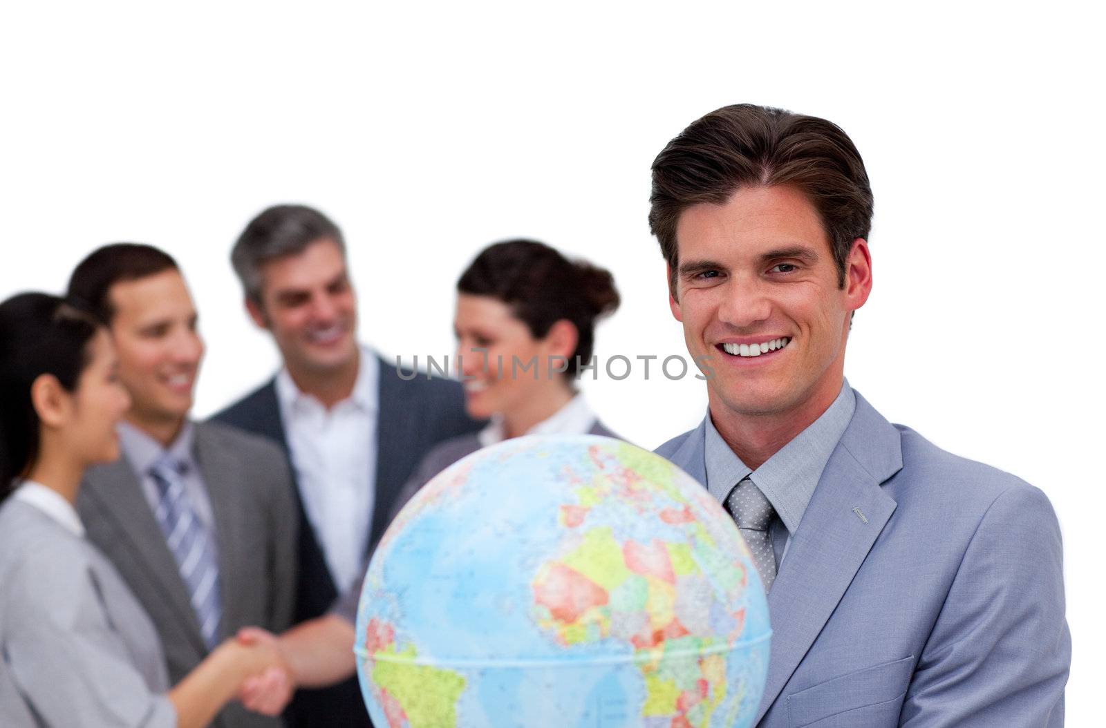 Happy businessman holding a globe in front of his team against a white background