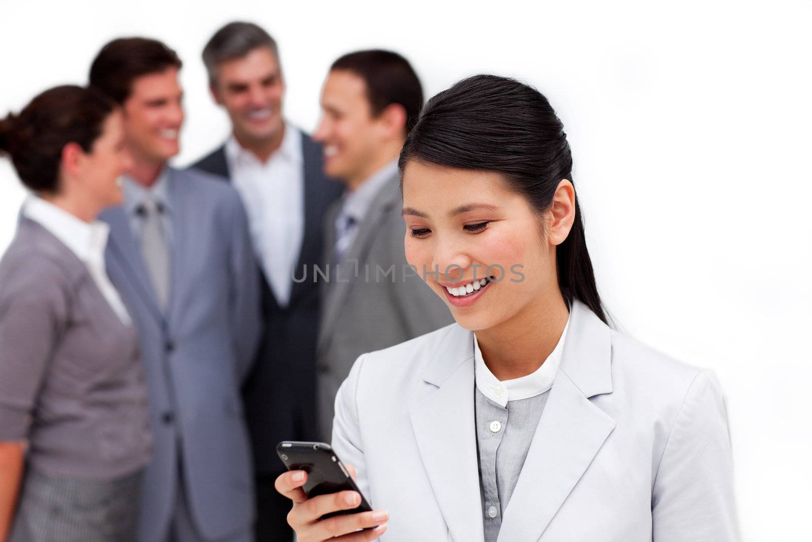 Asian businesswoman looking at her cellphone in front of her team against a white background