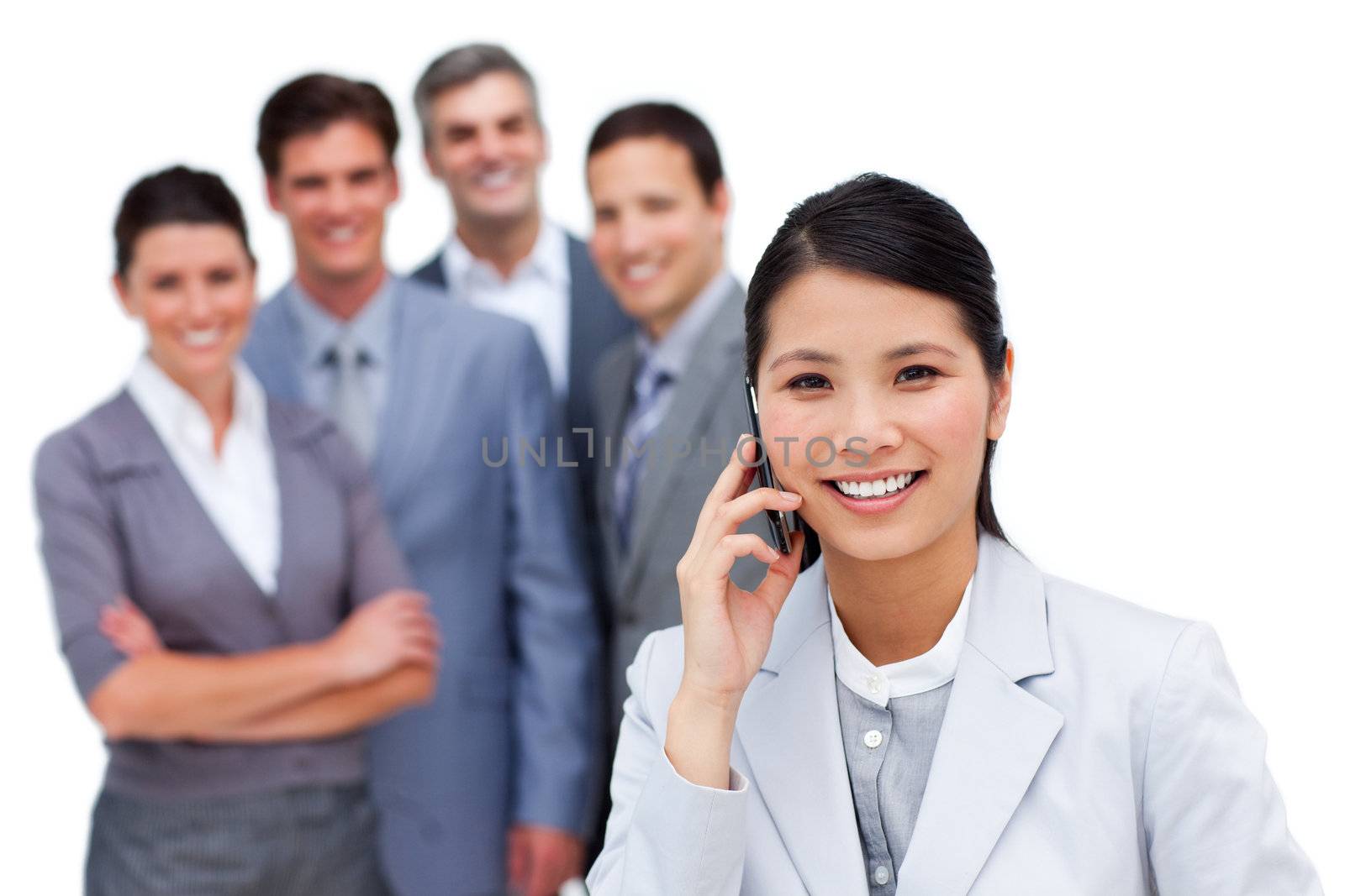Asian woman talking on phone in front of her team against a white background