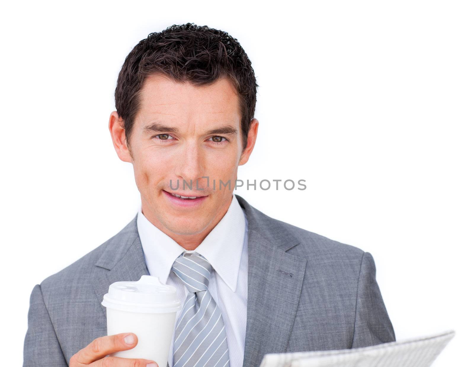 Male executive holding a drinking cup and reading a newspaper looking at the camera