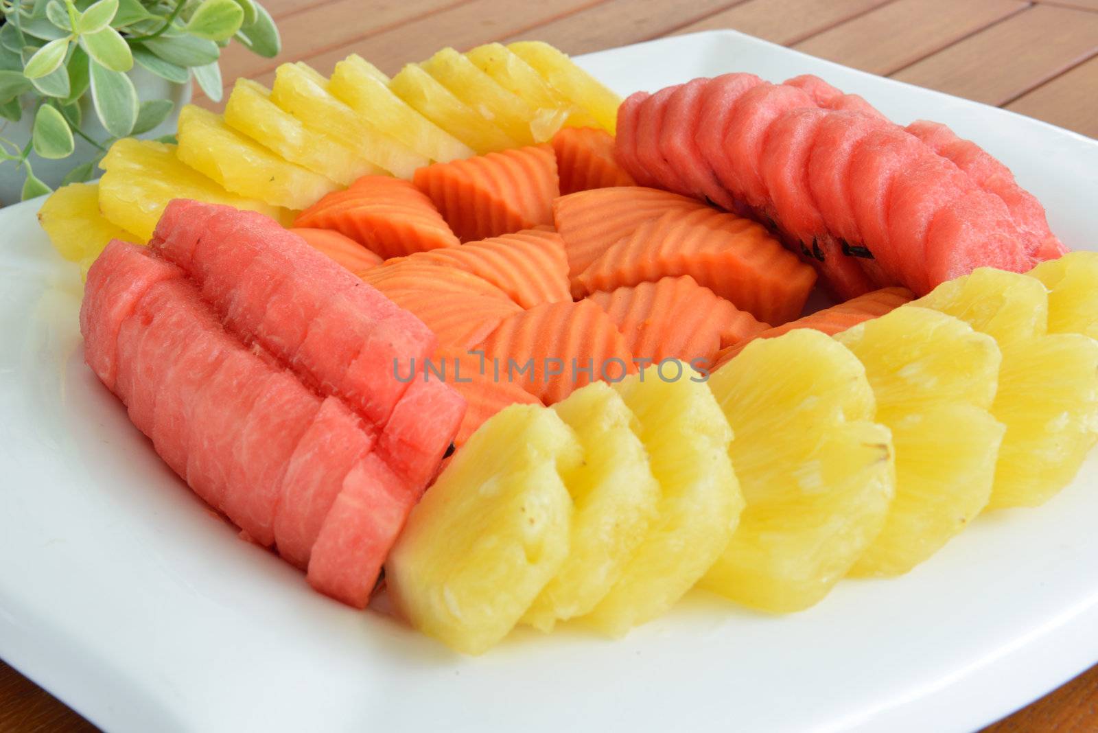 Mixed fruit including papaya, watermelon and pineapple is served on the white plate