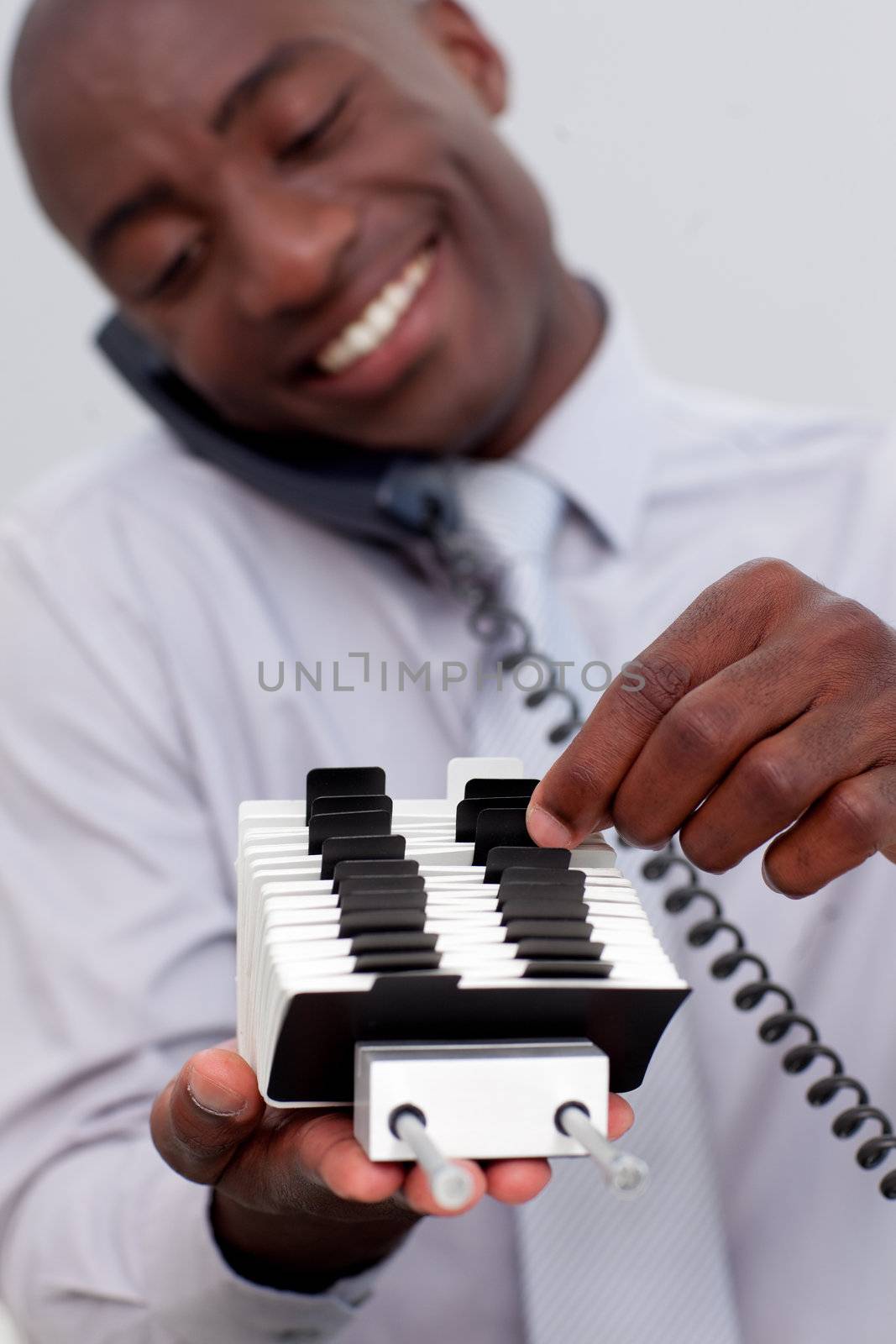 Afro-American businessman on phone searching for an index holder