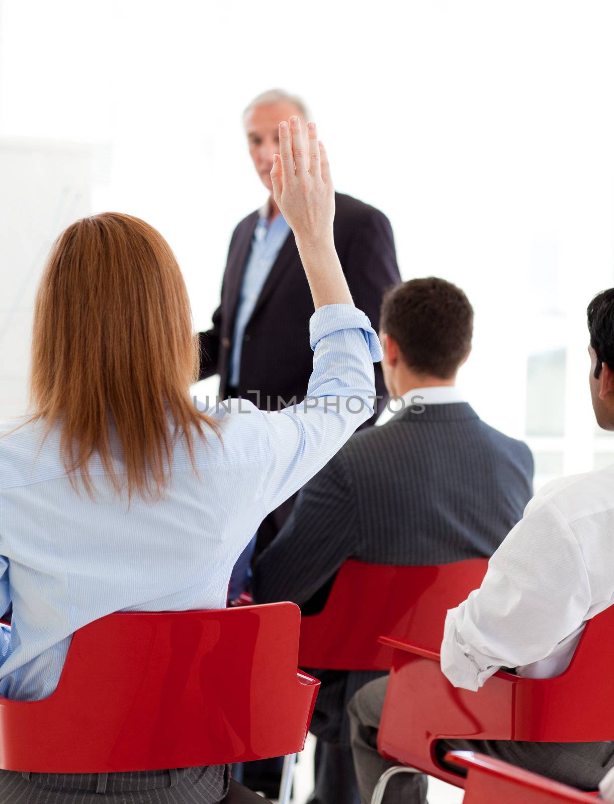 Businesswoman raising her hand up at a conference by Wavebreakmedia