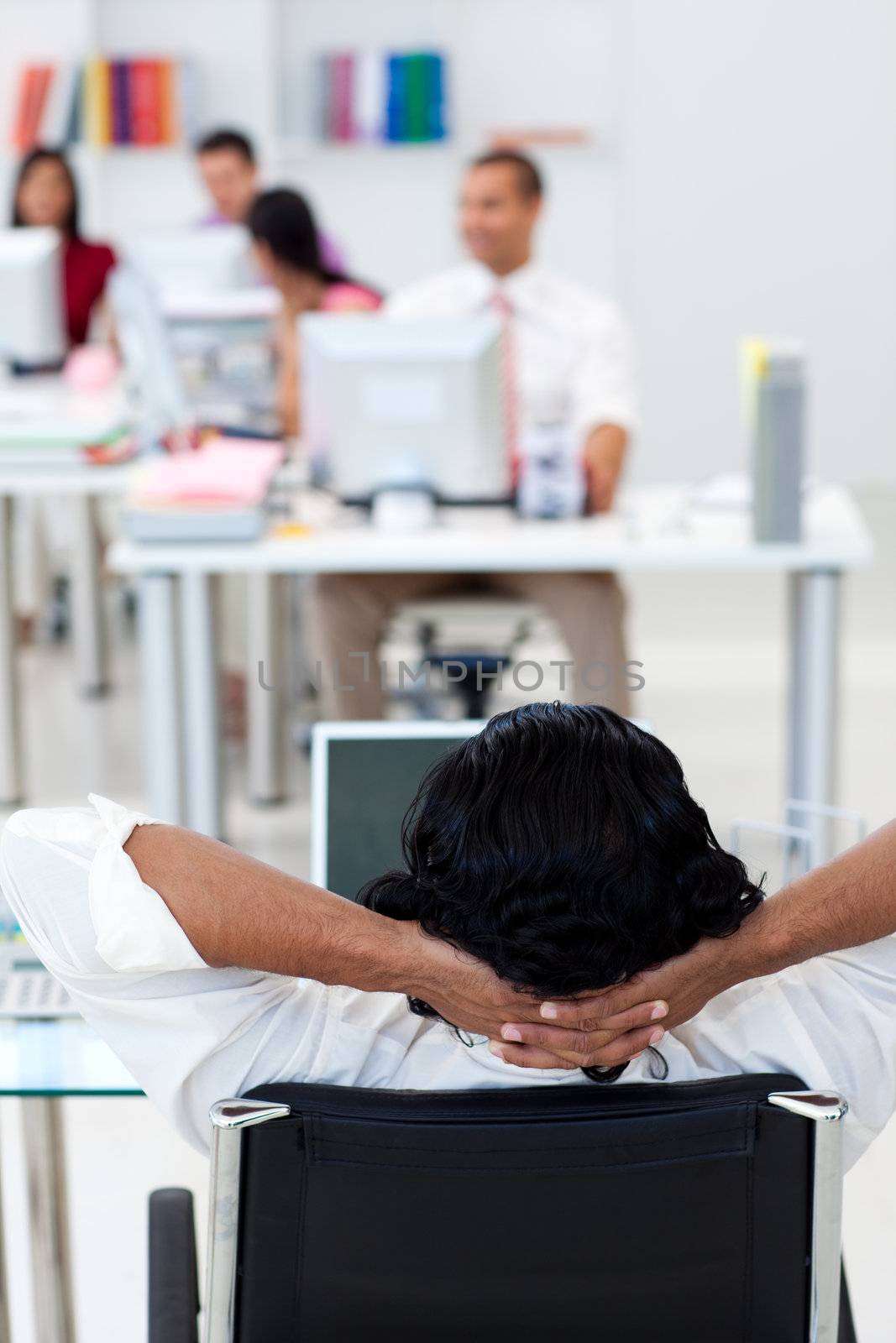 Businessman leaning back on a chair in front of his team in the office
