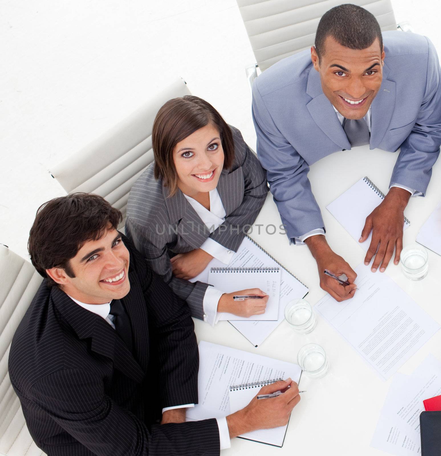 High angle of Three colleagues smiling at the camera in a meeting