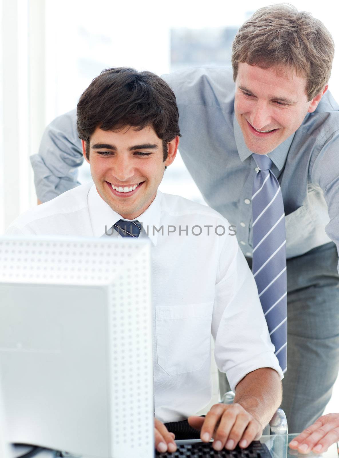 Two serious businessmen working at a computer in the office
