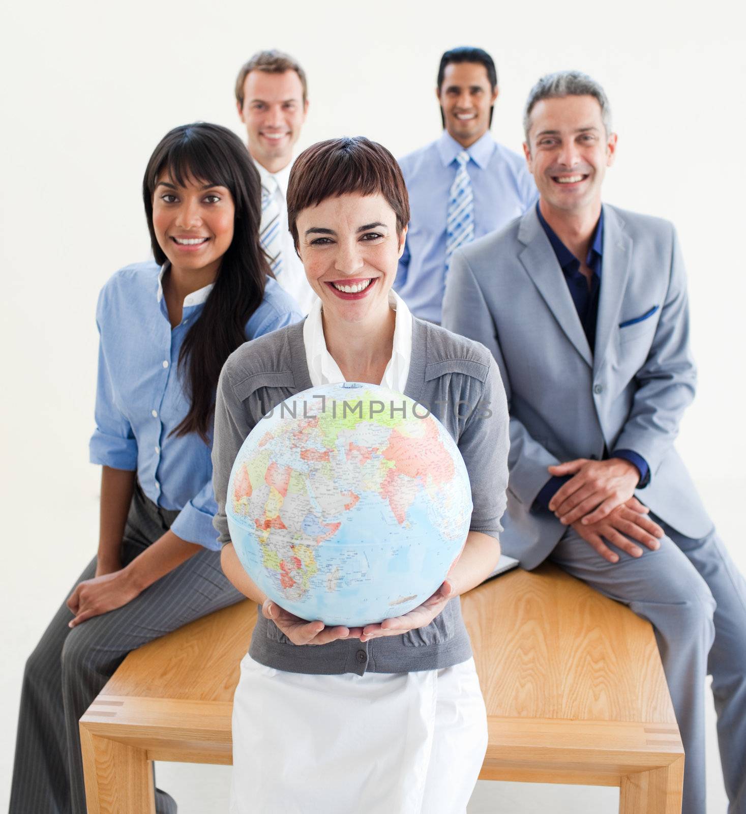Cheerful multi-ethnic business people holding a terrestrial globe in the office 