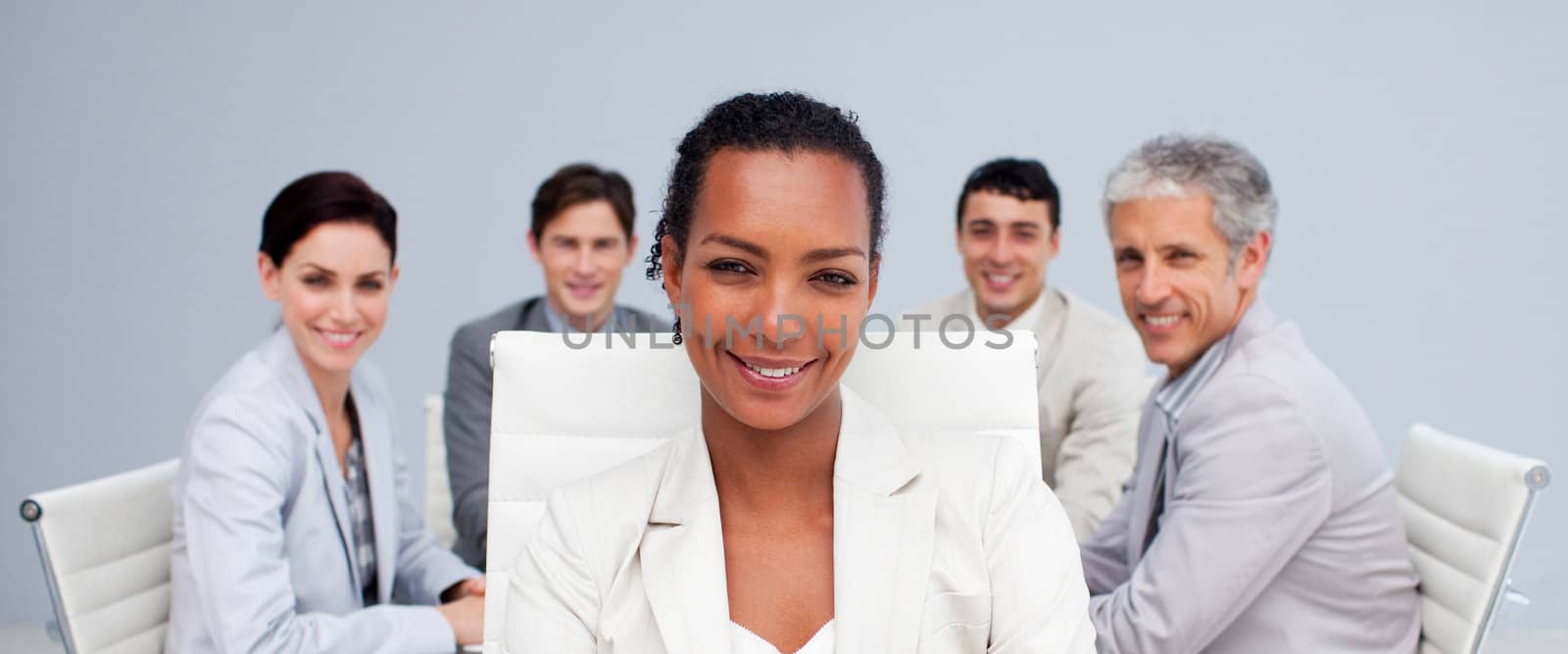 Afro-American businesswoman smiling in a meeting with her colleagues working in the background