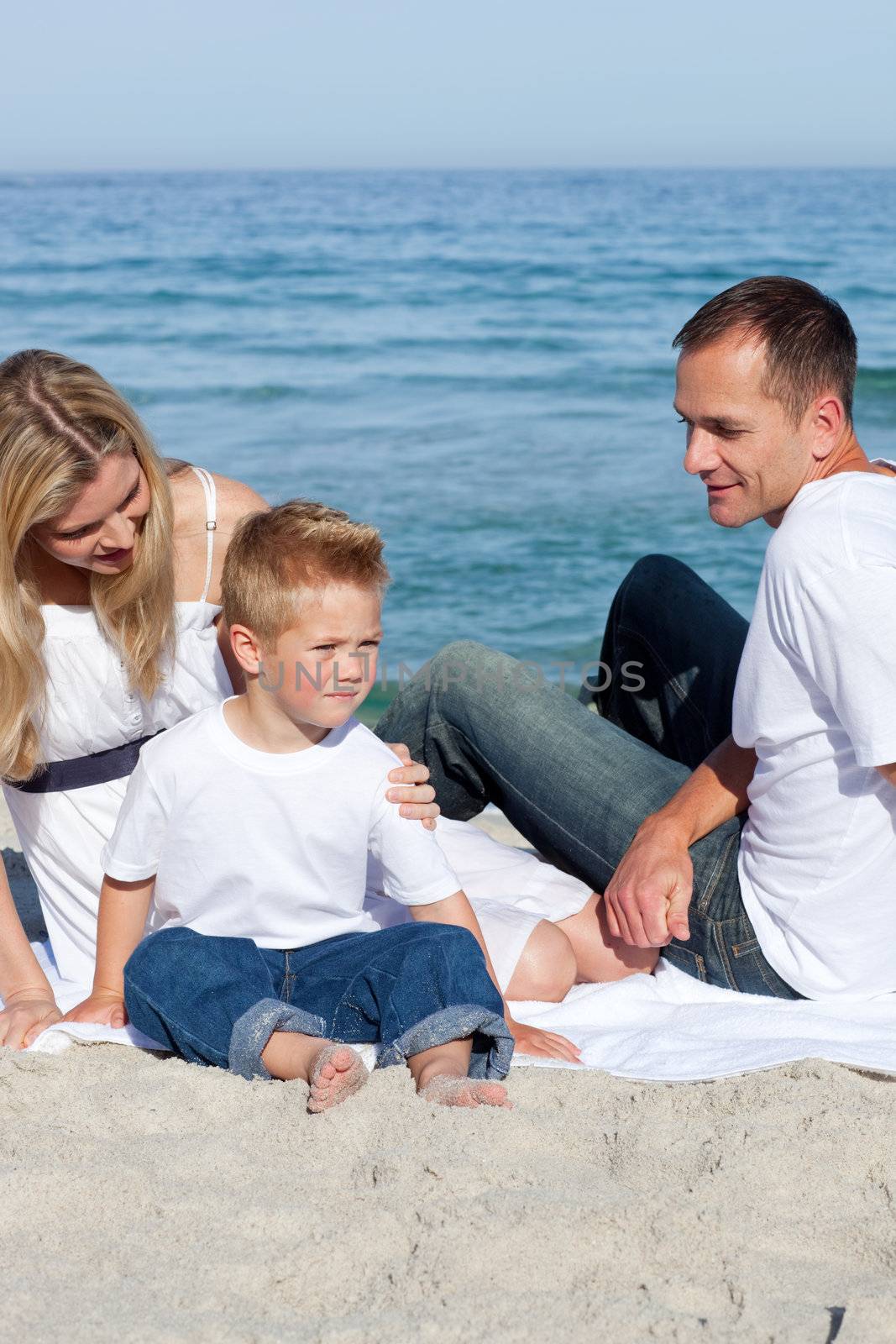 Happy parents with their son sitting on the sand  by Wavebreakmedia