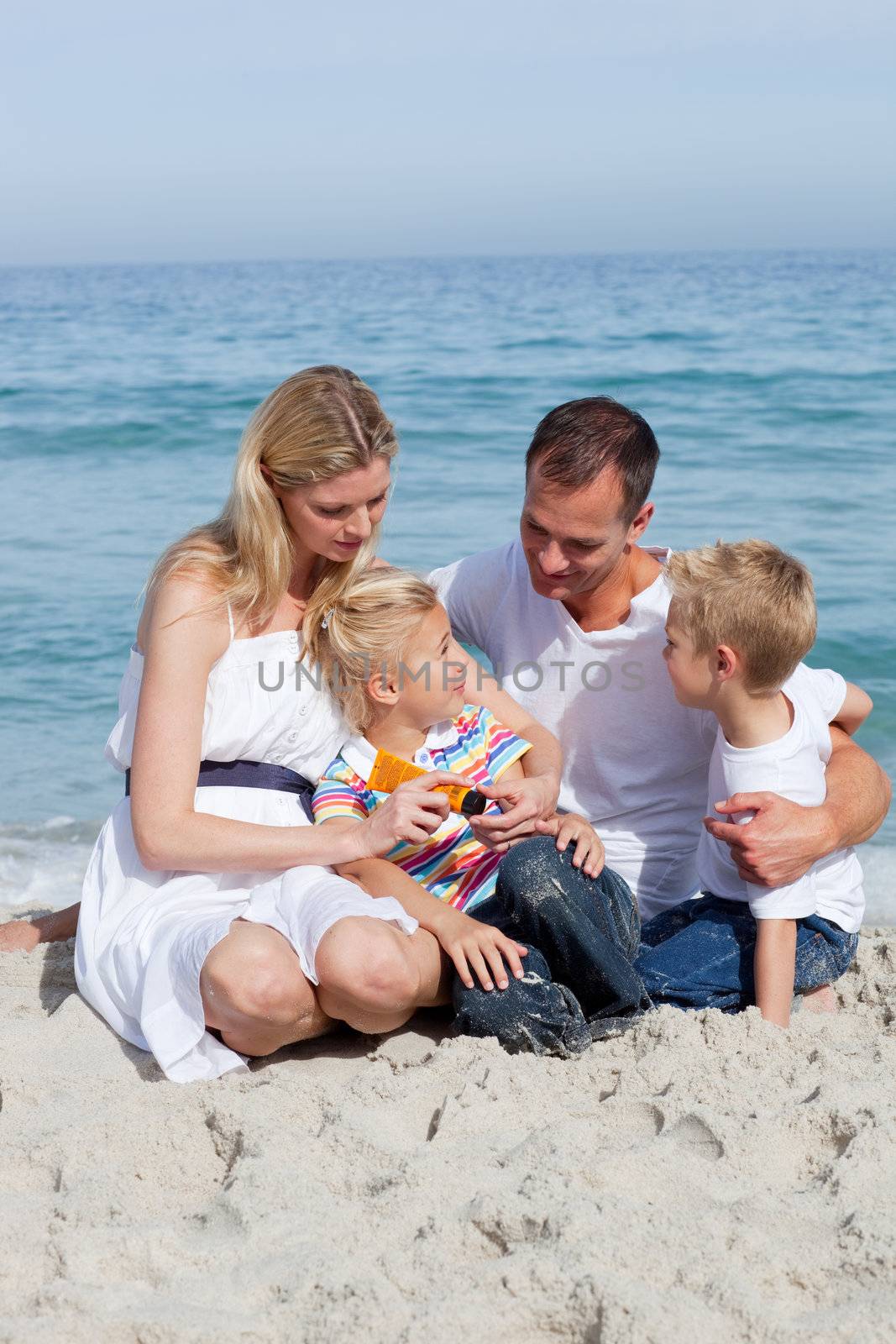 Caring mother with her family holding sunscreen at the beach 