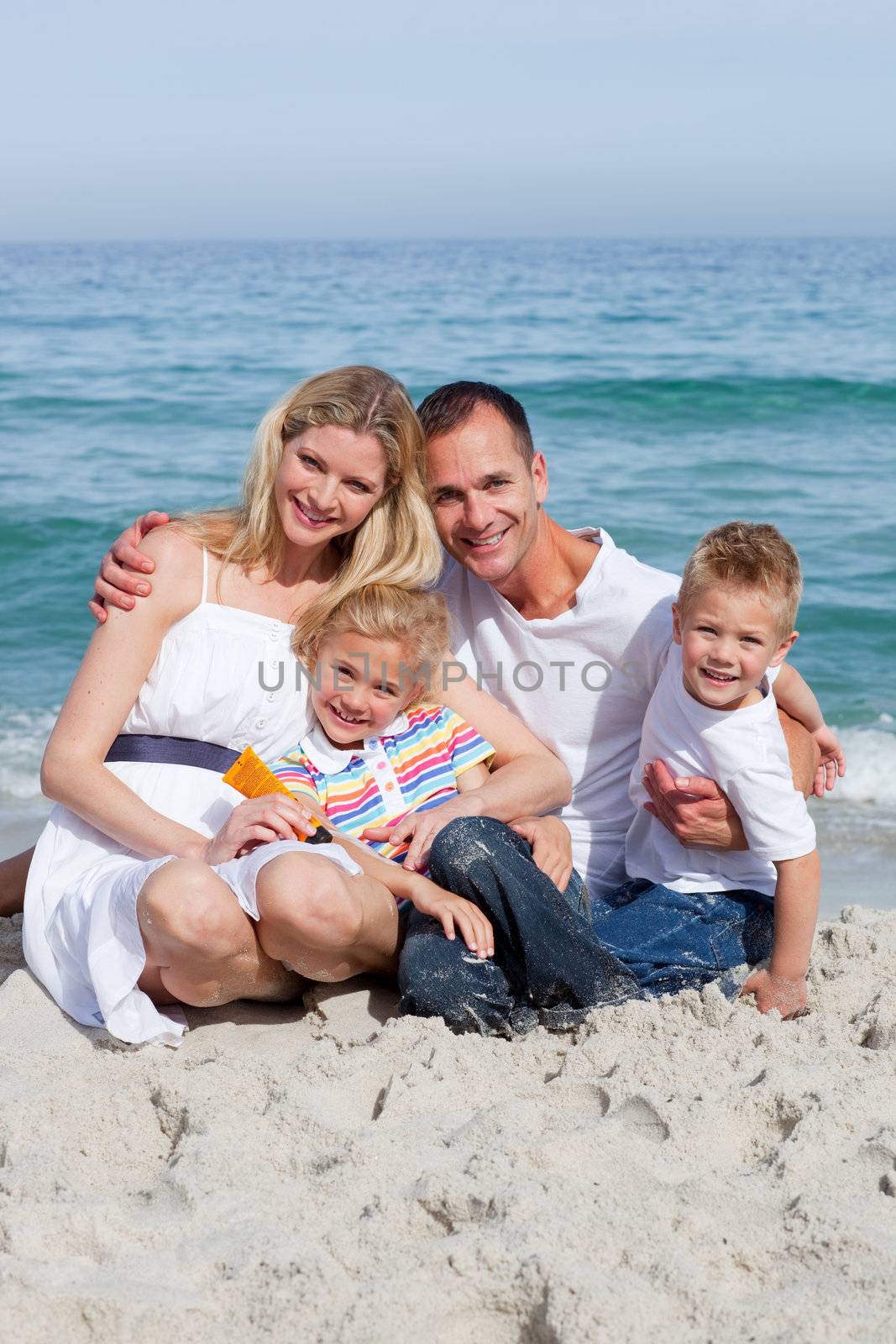 Portrait f a cheerful family holding suncreen at the beach