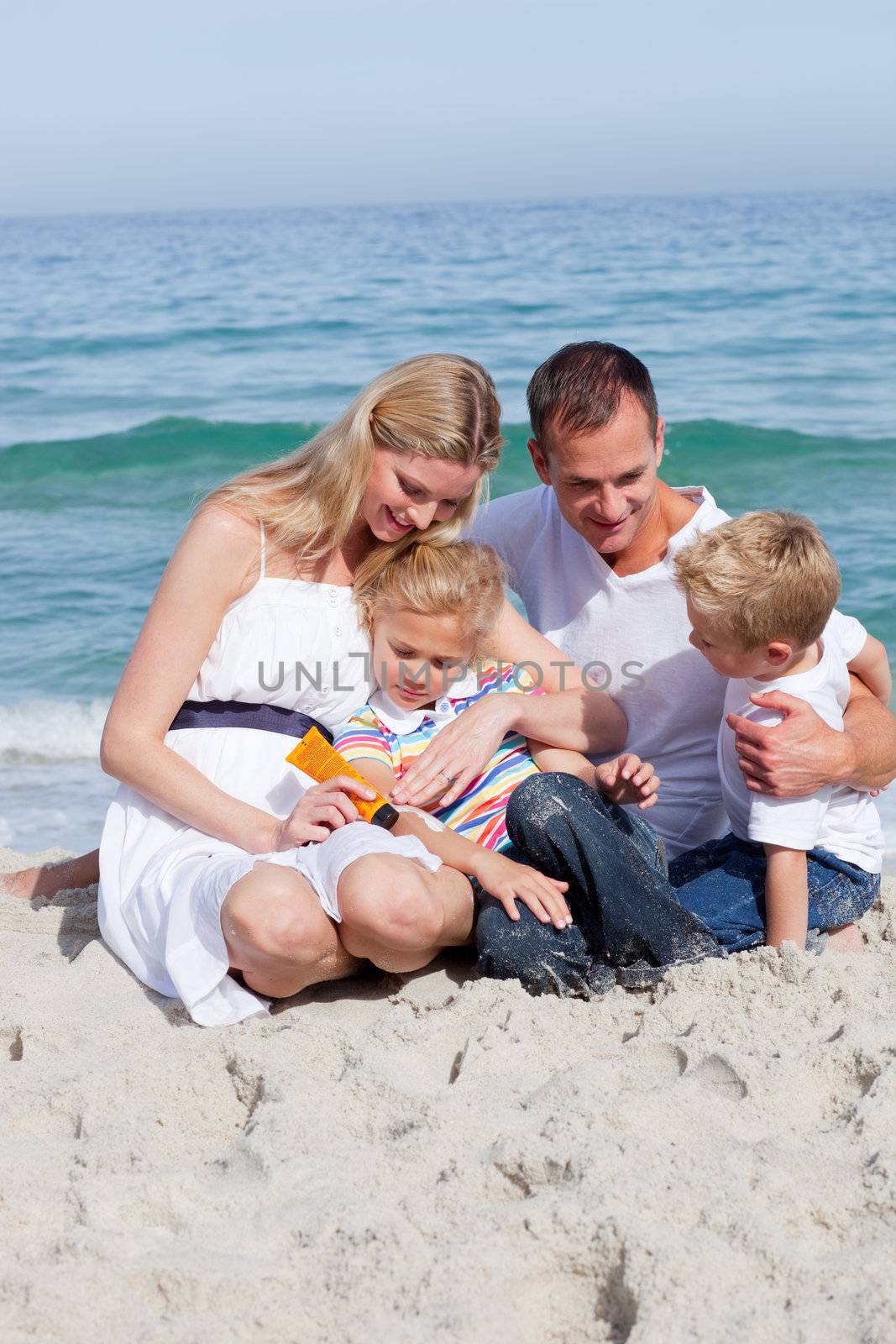 Smiling mother with her family holding sunscreen at the beach 