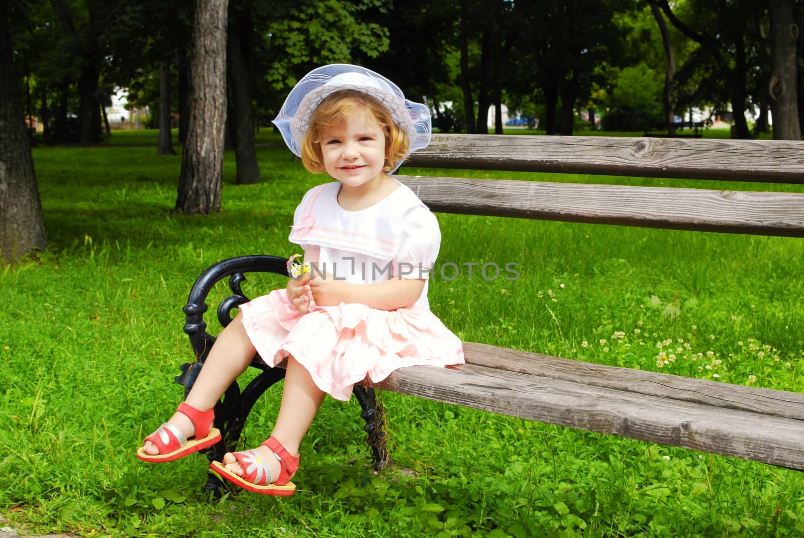 Little girl sitting on the bench in park