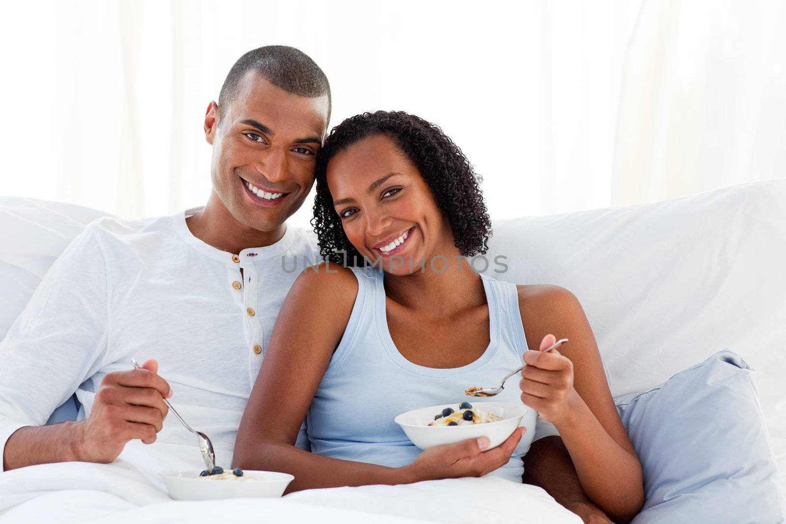 Romantic couple having breakfast lying on their bed