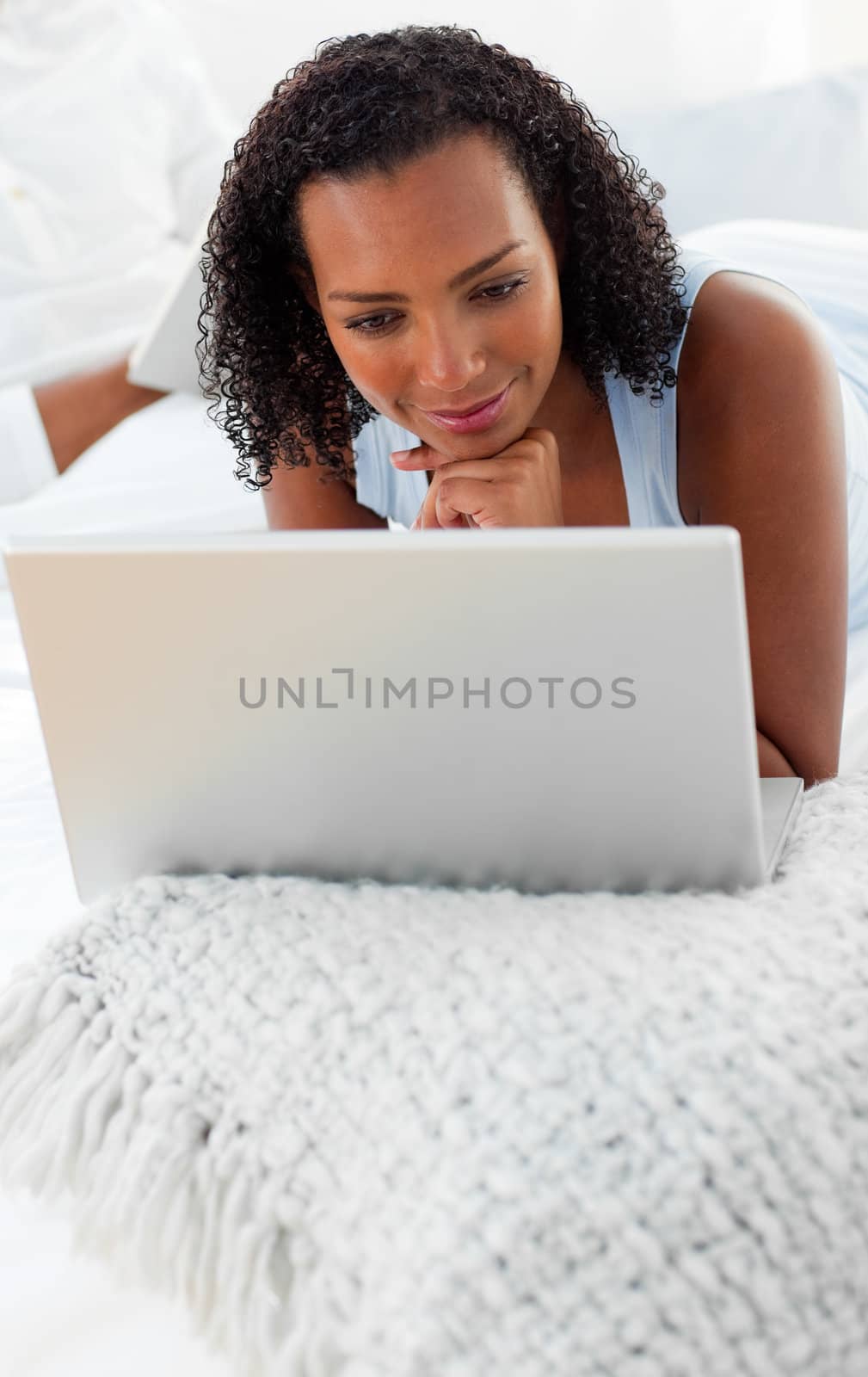 Smiling woman using a laptop on her bed by Wavebreakmedia