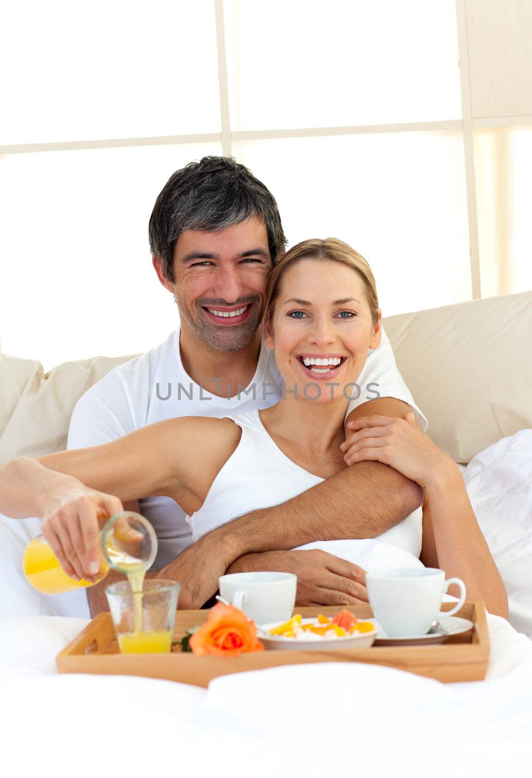 Romantic couple having breakfast lying in the bed by Wavebreakmedia