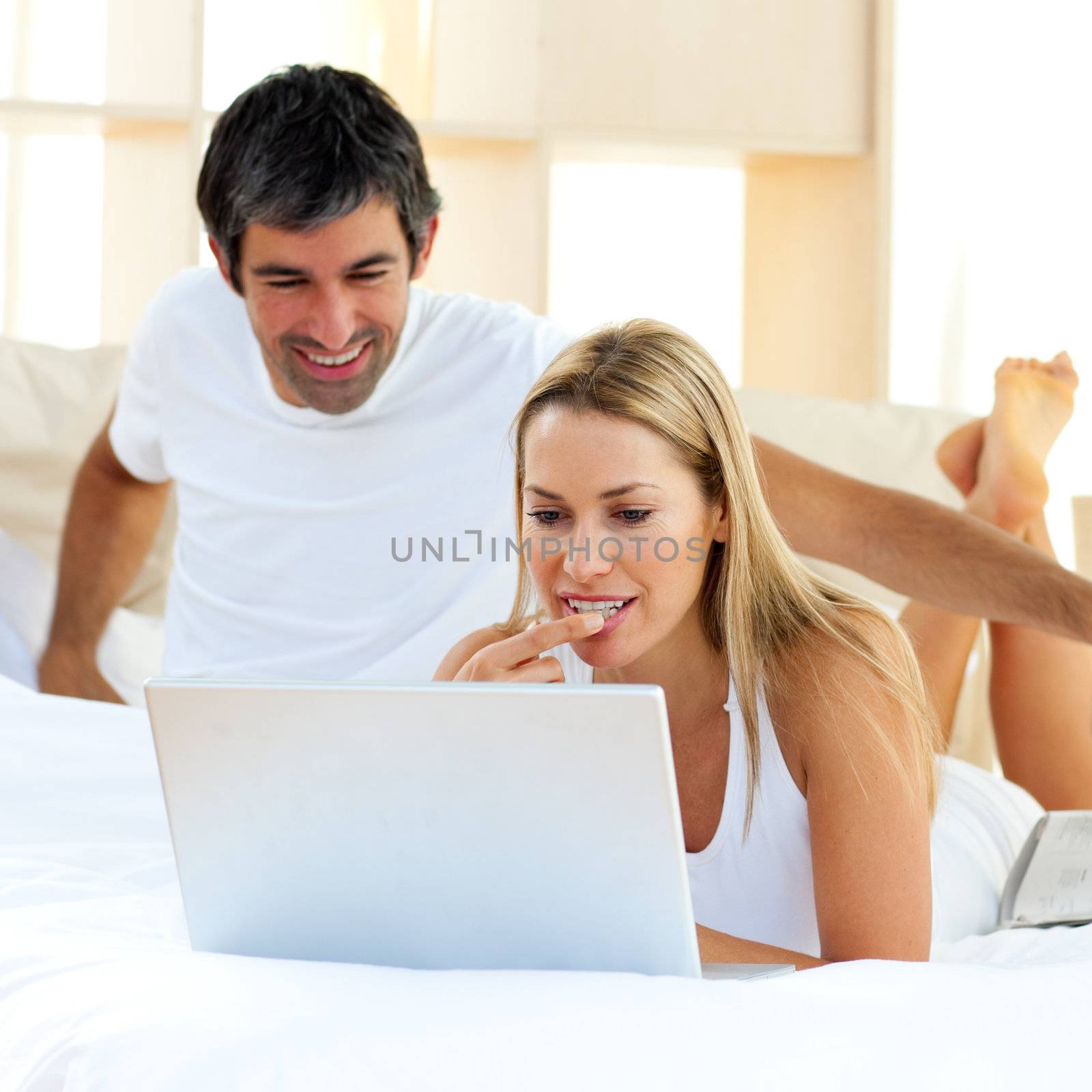 Assertive woman using a laptop lying on bed by Wavebreakmedia