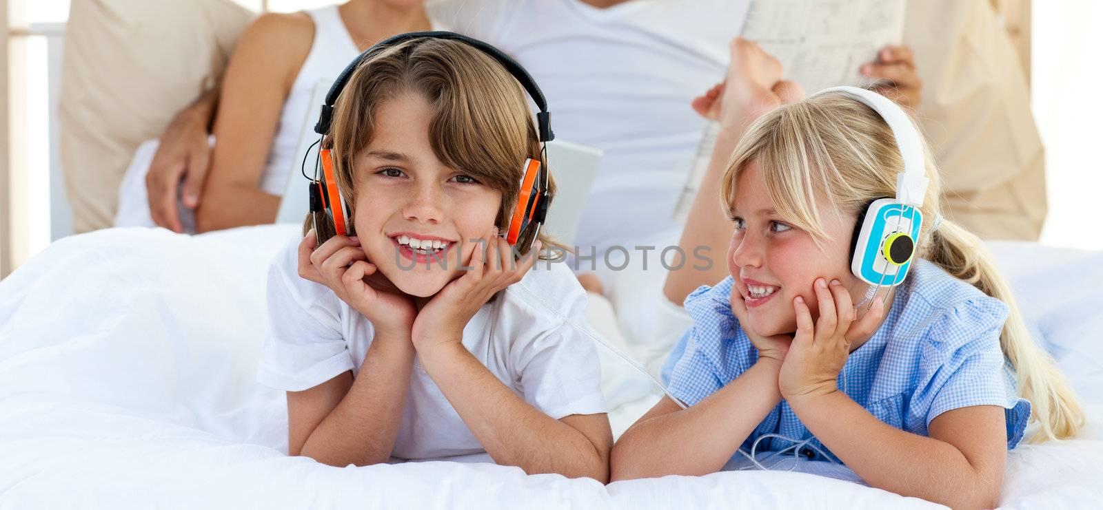 Close-up of brother and sister listening music lying on bed