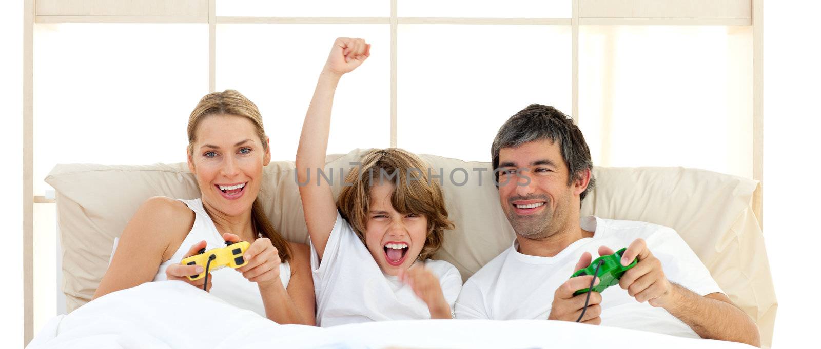 Smiling little boy playing video game with his family in the bedroom