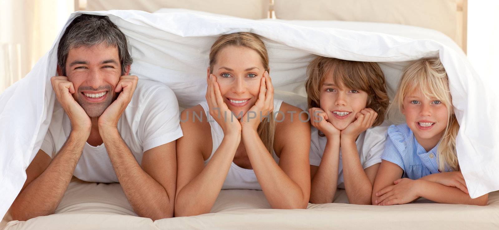Portrait of a attentive parents with their children playing on a bed