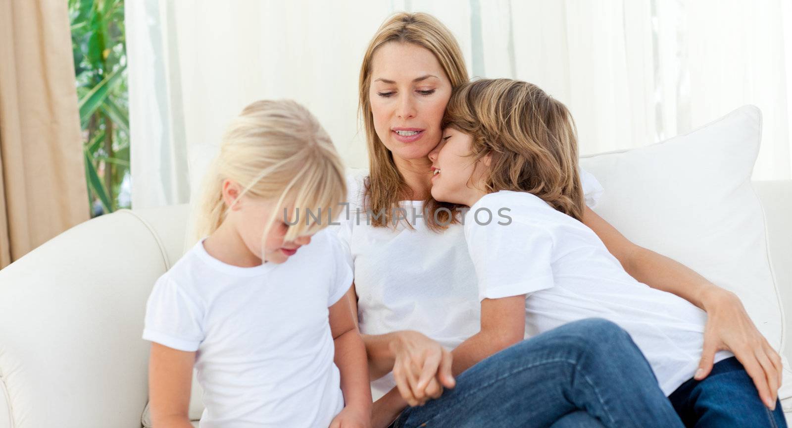 Blond mother having fun with her children sitting on sofa