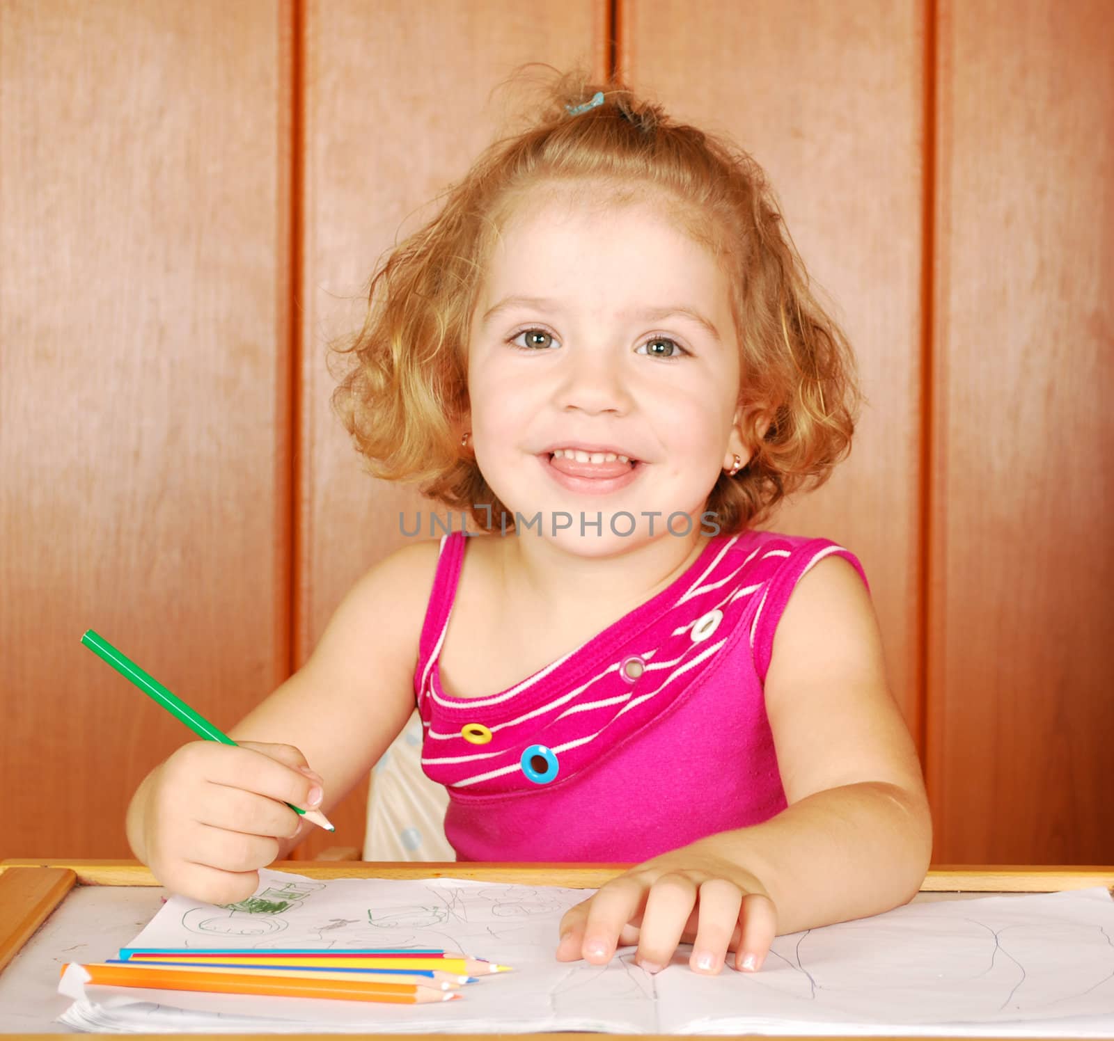 Happy little girl drawing with crayons