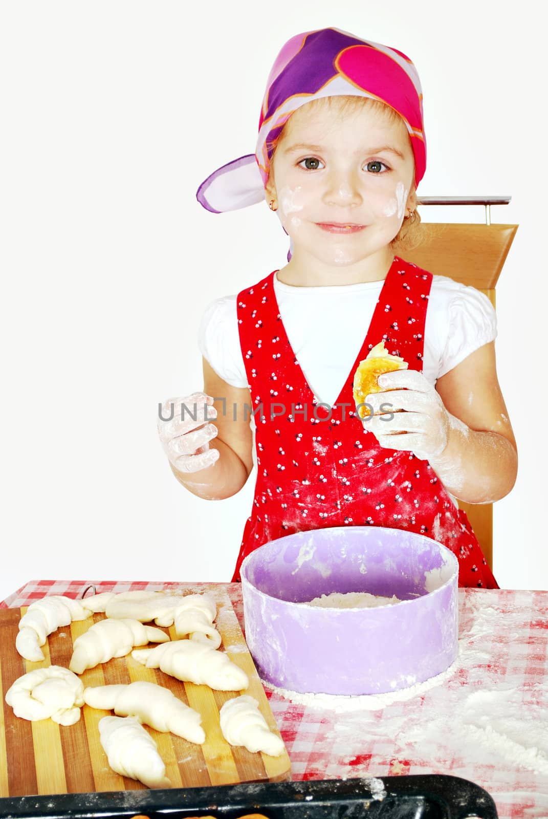 Little girl make and eat croissant studio shot