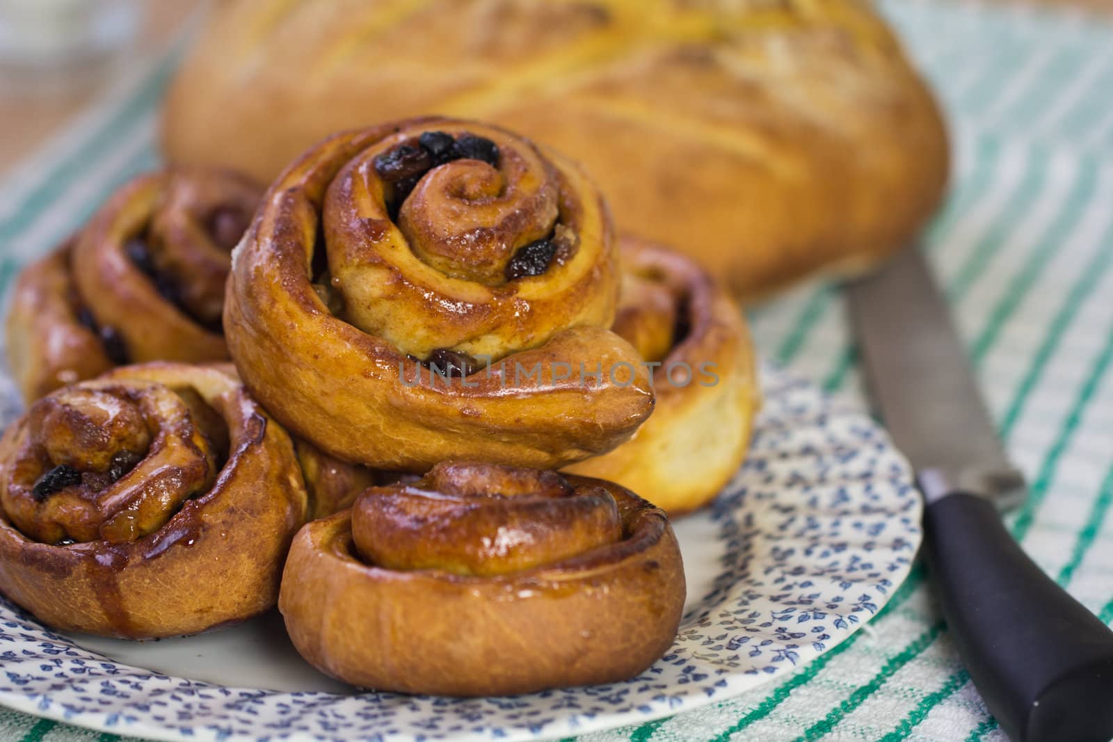 Fresh sticky Chelsea buns and a loaf of bread with knife