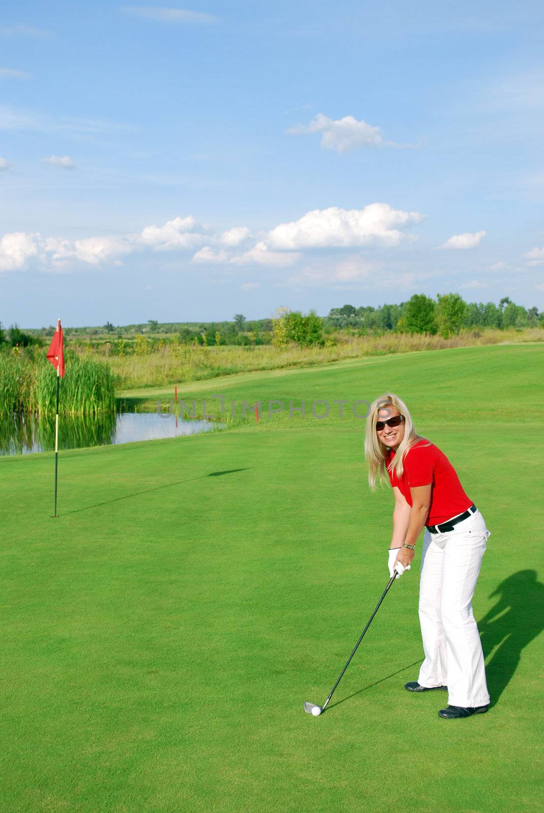 Blonde girl on golf field playing golf