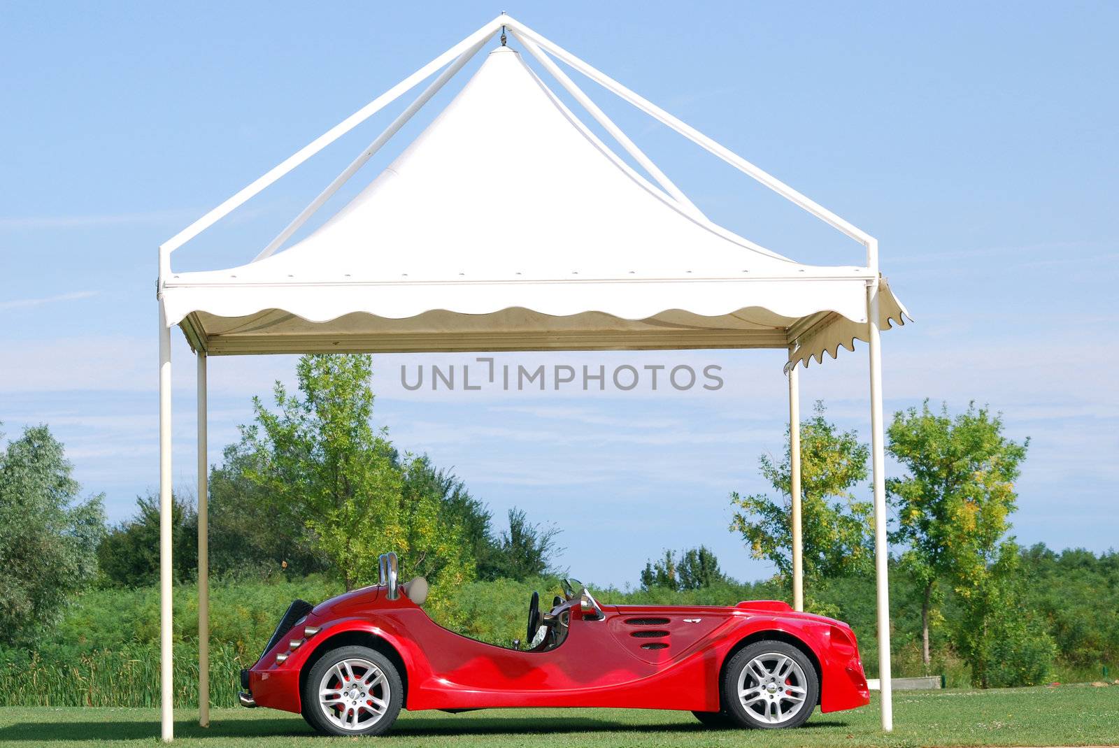 Fast red cabriolet car under white tent