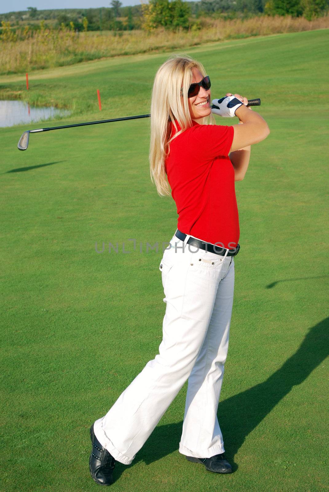 Blonde girl golf player on golf field