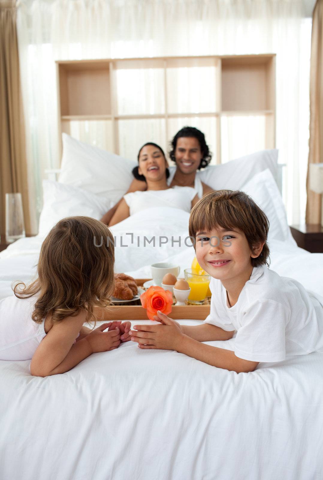 Happy children bringing a breakfast to their parents in the bedroom