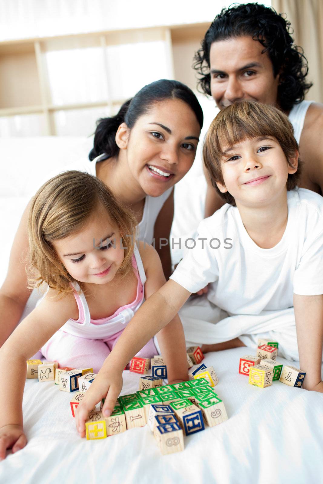 Young family having fun with alphabetics blocks on the bed