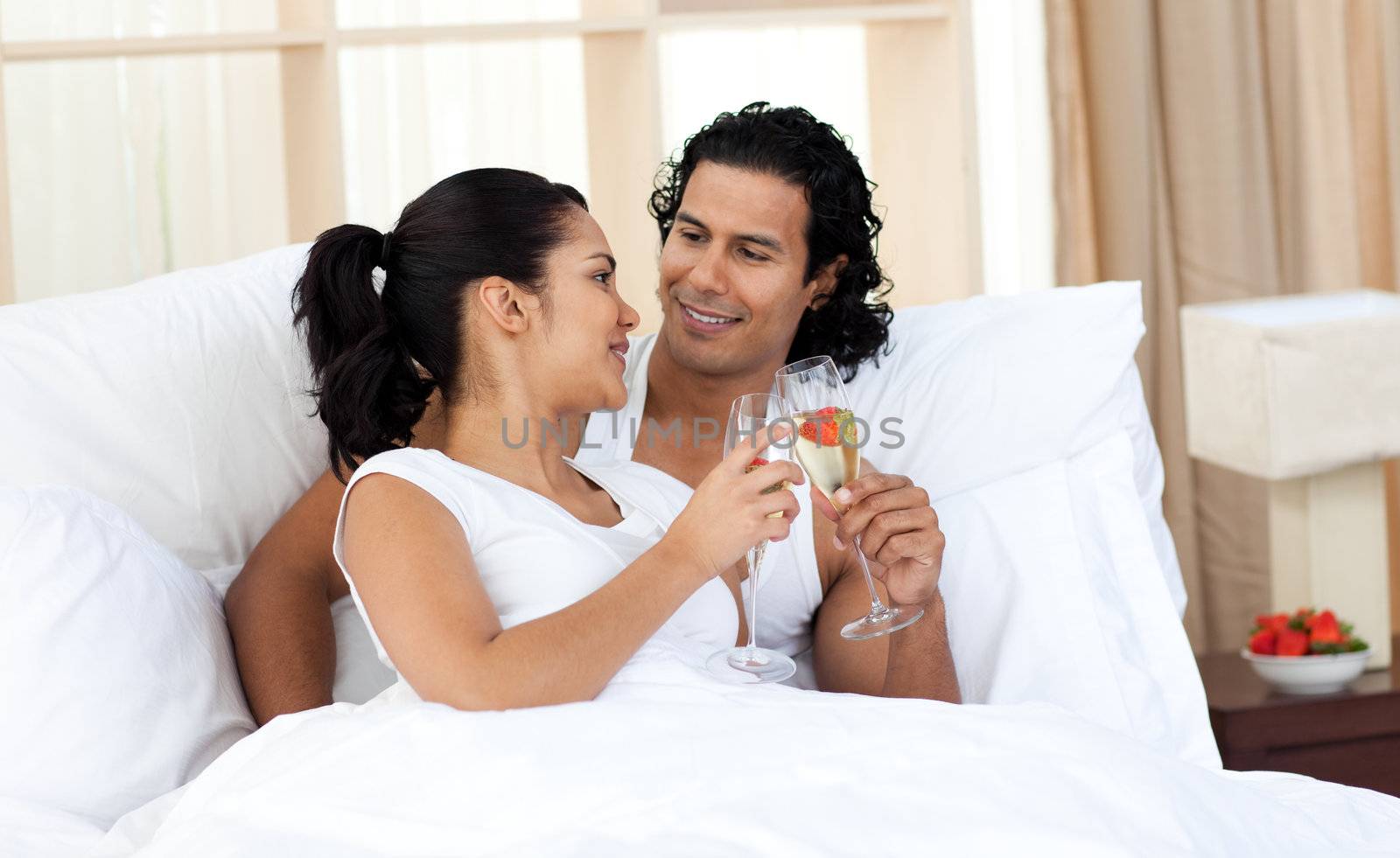 Lovers toasting with Champagne in the bedroom by Wavebreakmedia