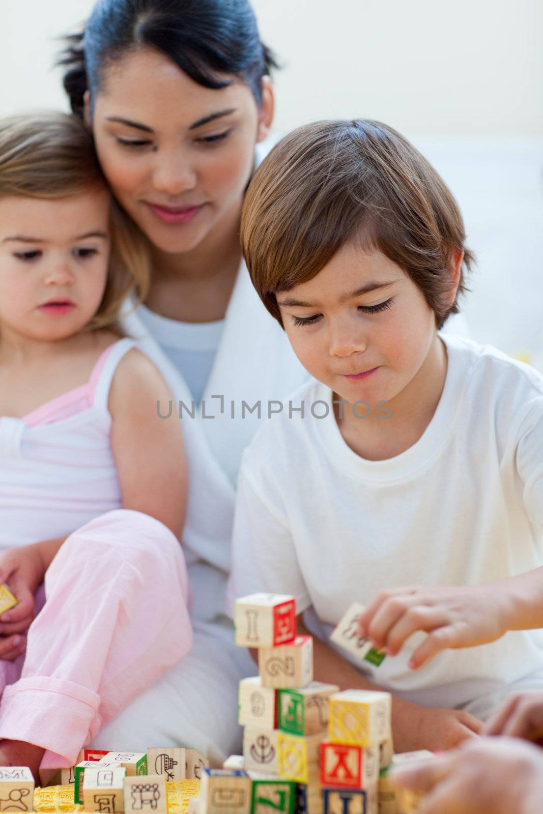 Mother and children playing with alphabetics blocks in the bedroom