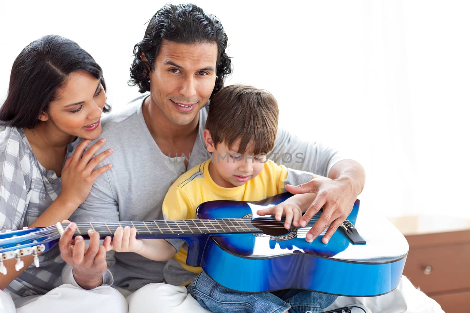 Cute little boy playing guitar with his parents at home