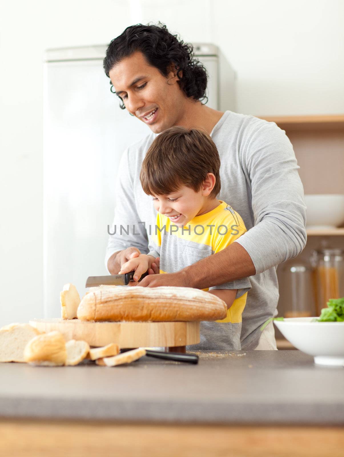 Attentive father helping his son cut some bread in the kitchen