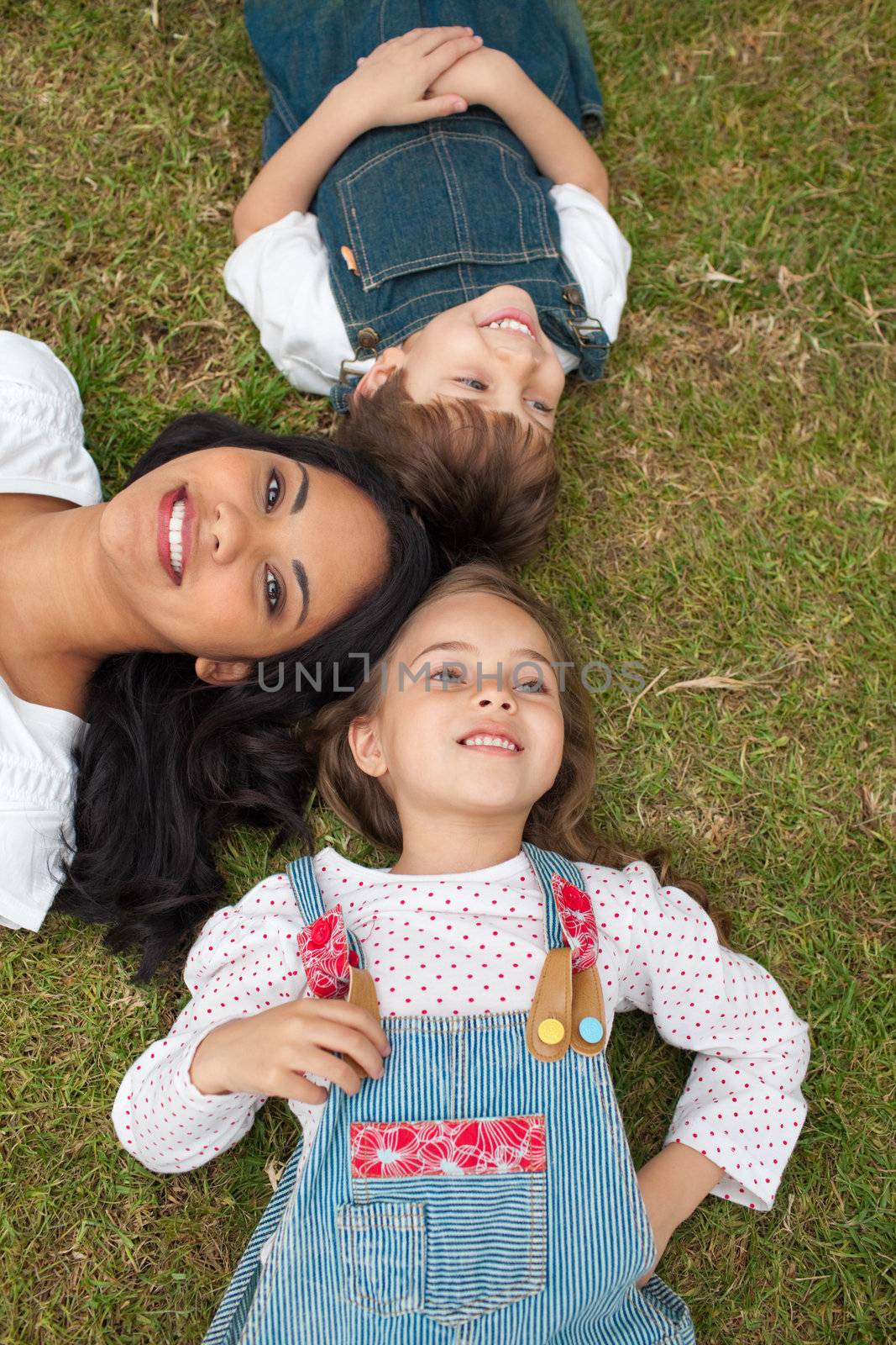 Happy mother and her children lying on the grass in a park