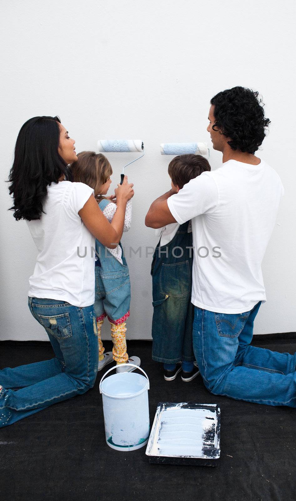 Attentive parents helping their children paint wall