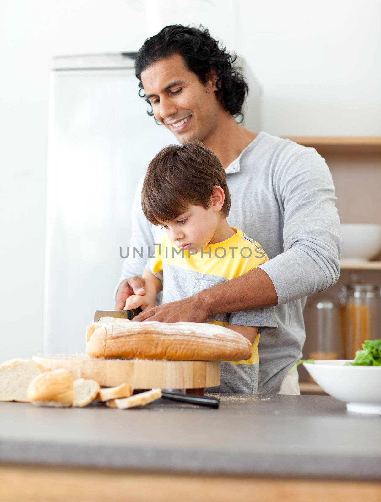 Charming father cutting bread with his son in the kitchen