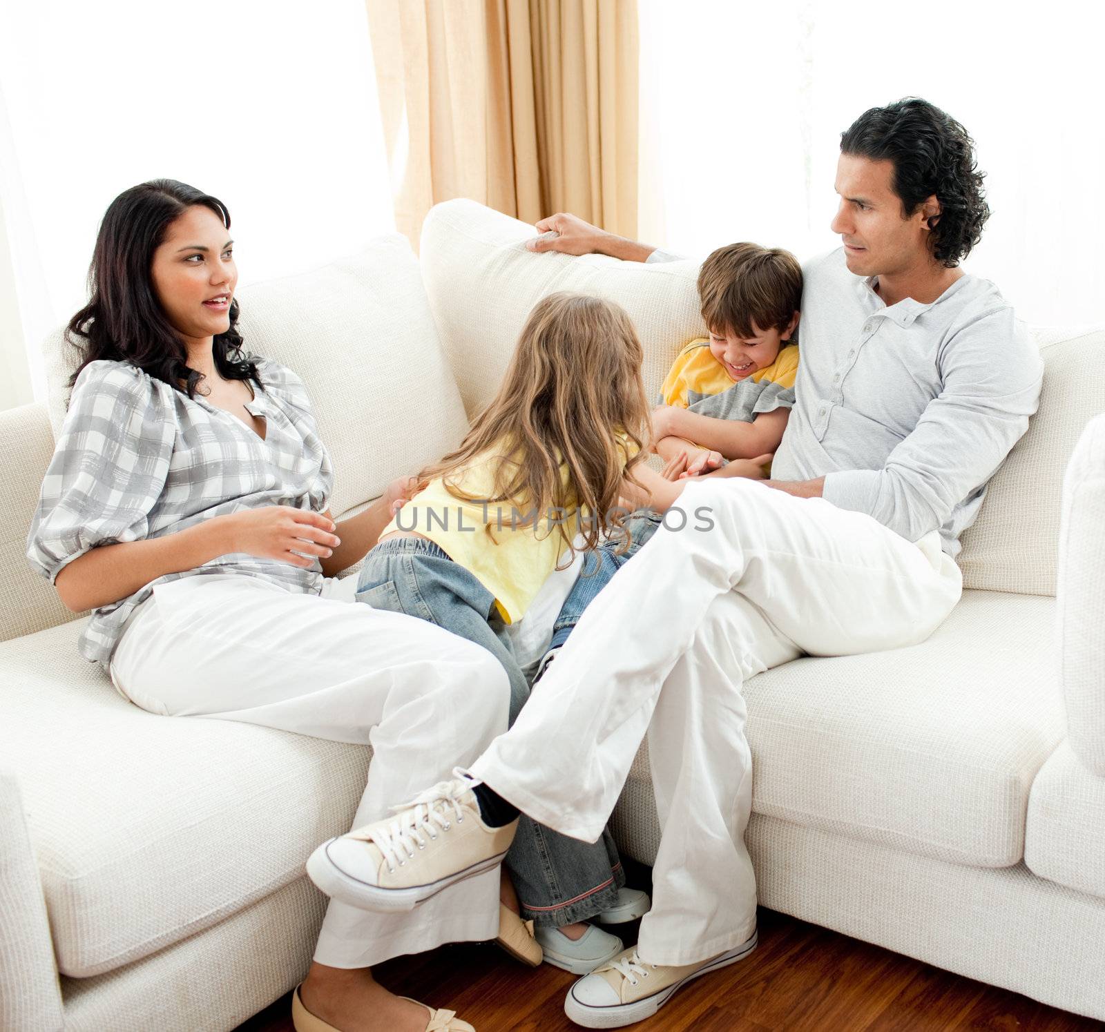 Attentive parents sitting on sofa with their children by Wavebreakmedia